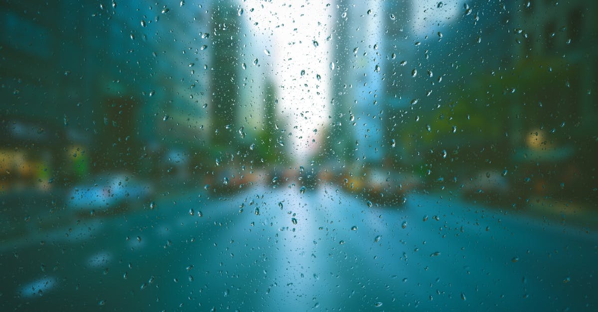 Blurred city scene through raindrop-covered window, creating a tranquil urban mood.